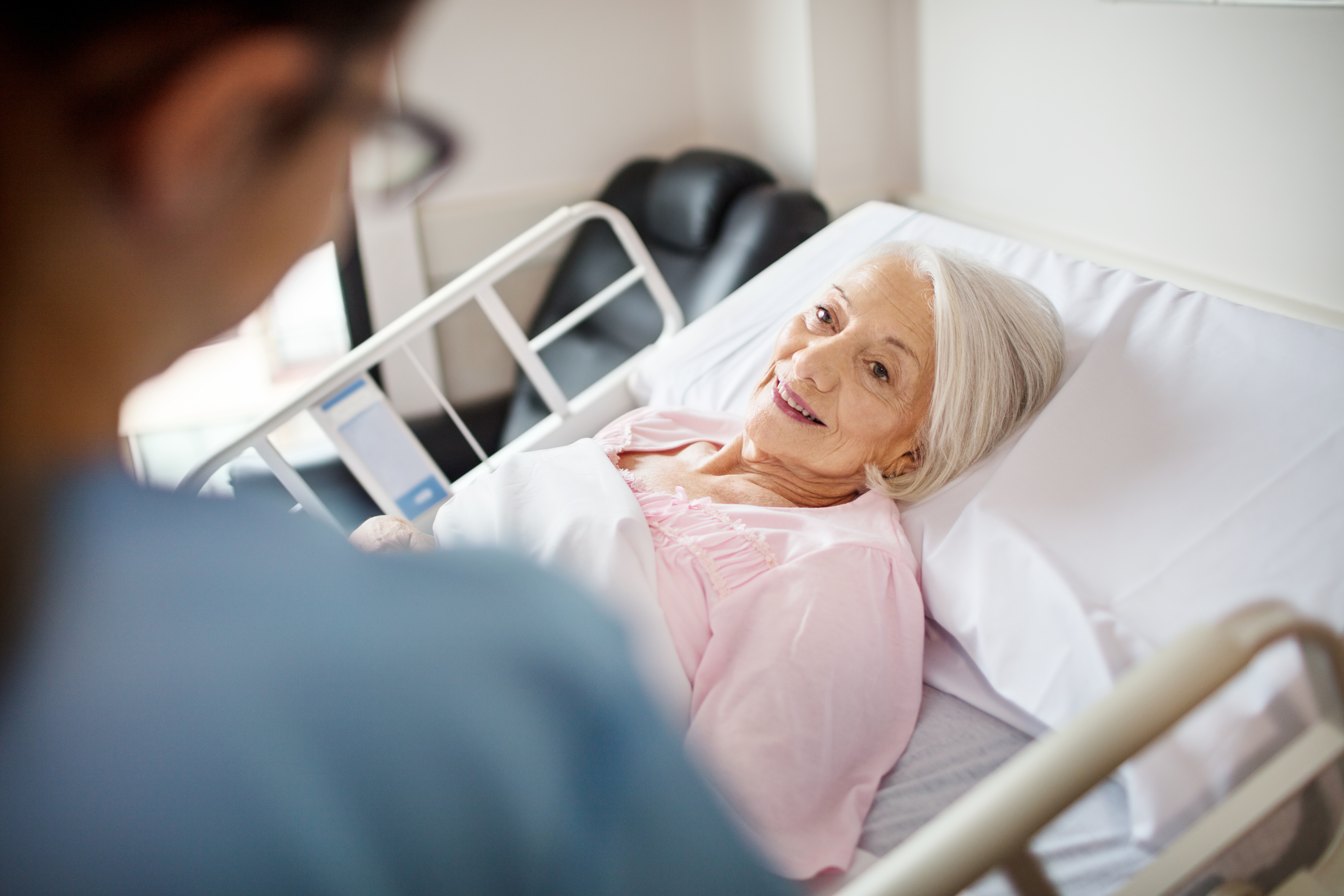 Senior woman smiling at female nurse in hospital