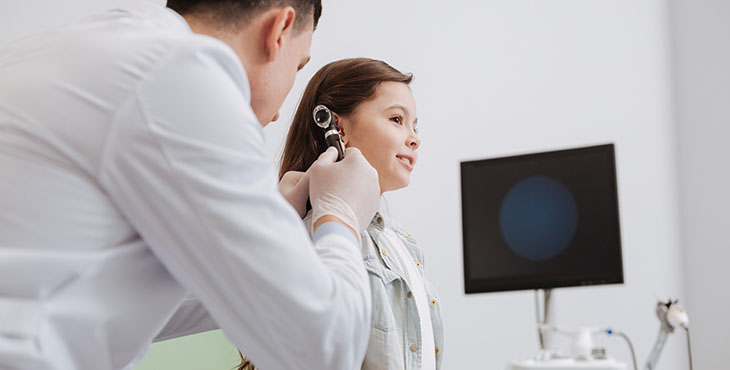 Competent pediatrician examining girls hearing
