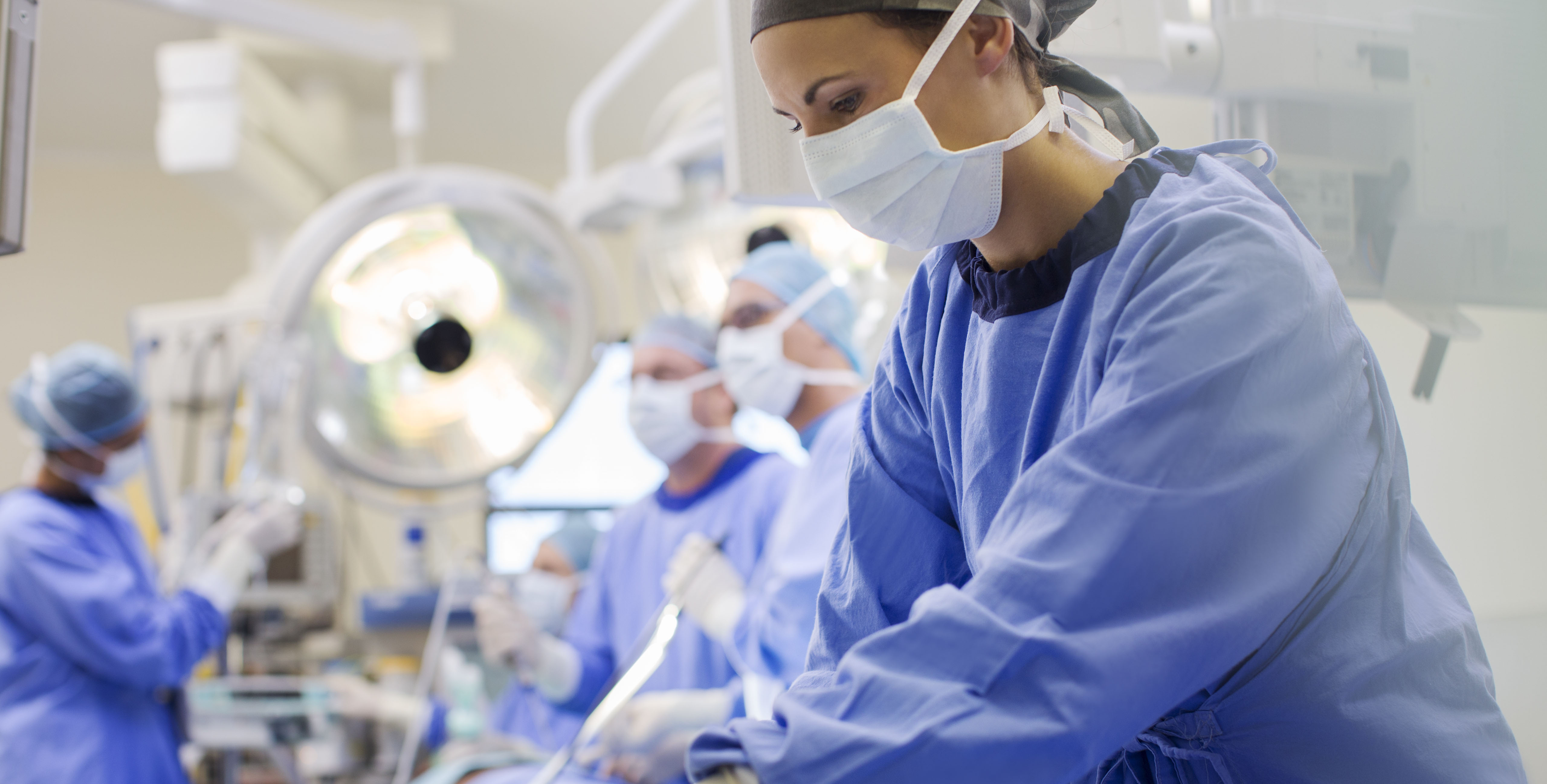 Nurse wearing scrubs preparing medical instruments in operating theater